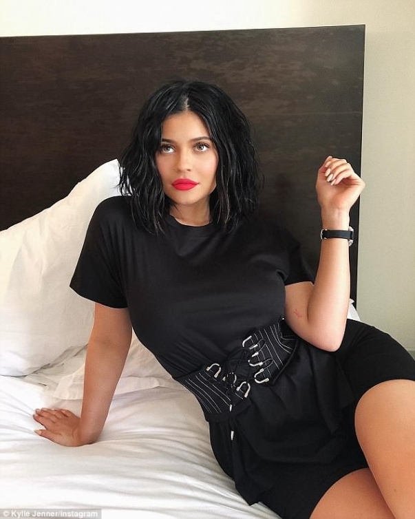 Kylie Jenner poses across her bed in black dress